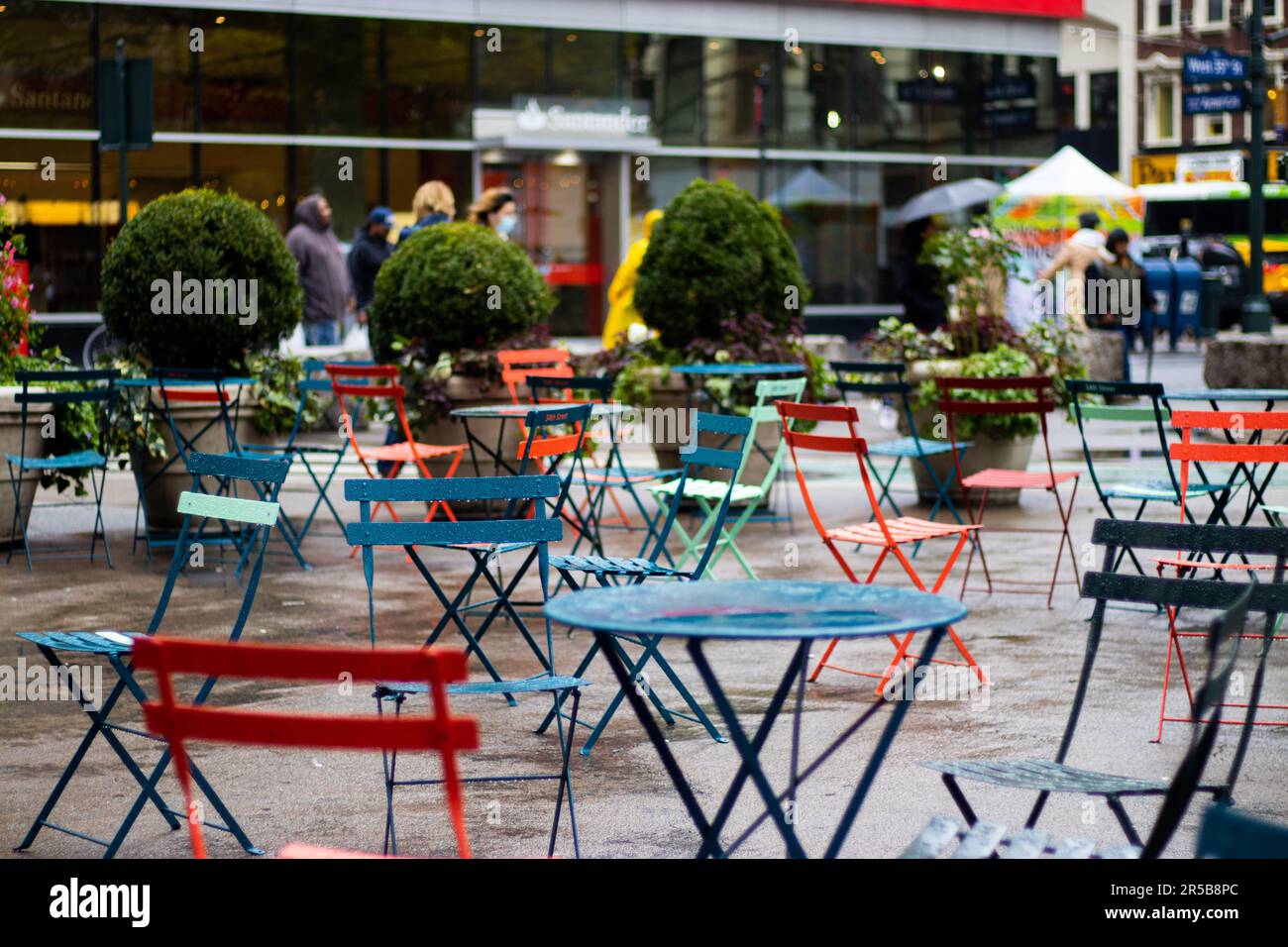 Un patio extérieur avec une variété de sièges et de tables, avec parasols colorés à l'ombre Banque D'Images