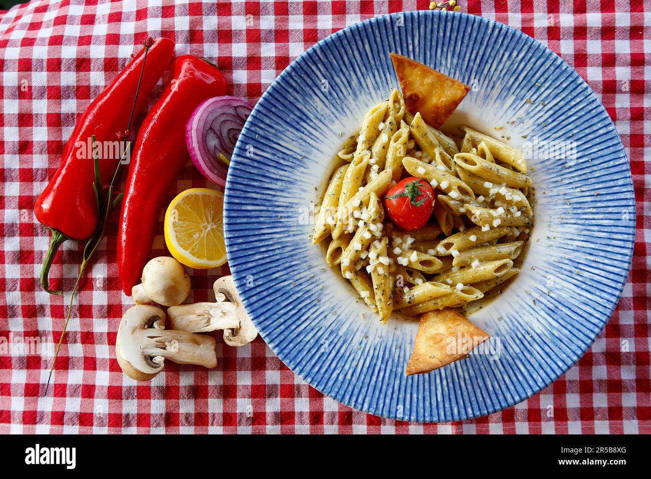 Une assiette de pâtes avec sauce pesto, champignons et autres légumes Banque D'Images