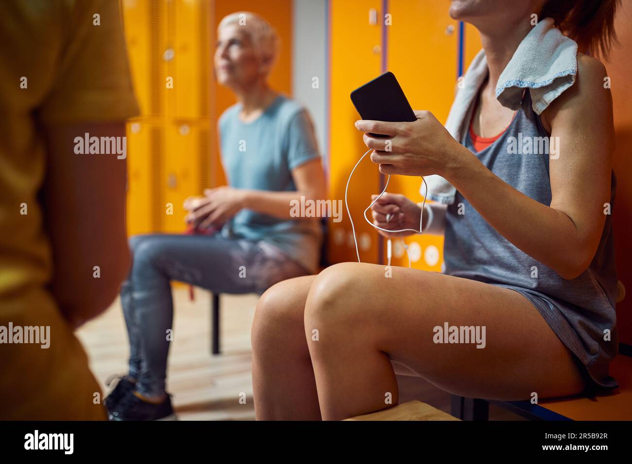 Trois femmes dans le vestiaire de la salle de gym, assis et parlant après l'entraînement. Concept de santé, de bien-être, de mode de vie. Banque D'Images