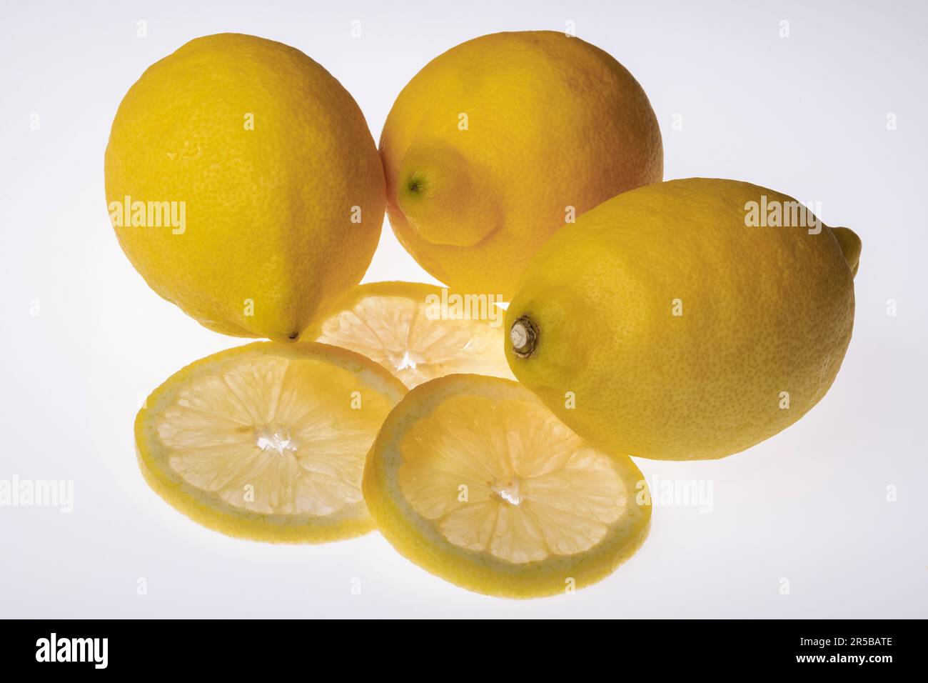 citrons fraîchement tranchés, accompagnés de citrons entiers. Photo du produit avec des tranches de shone à travers Banque D'Images
