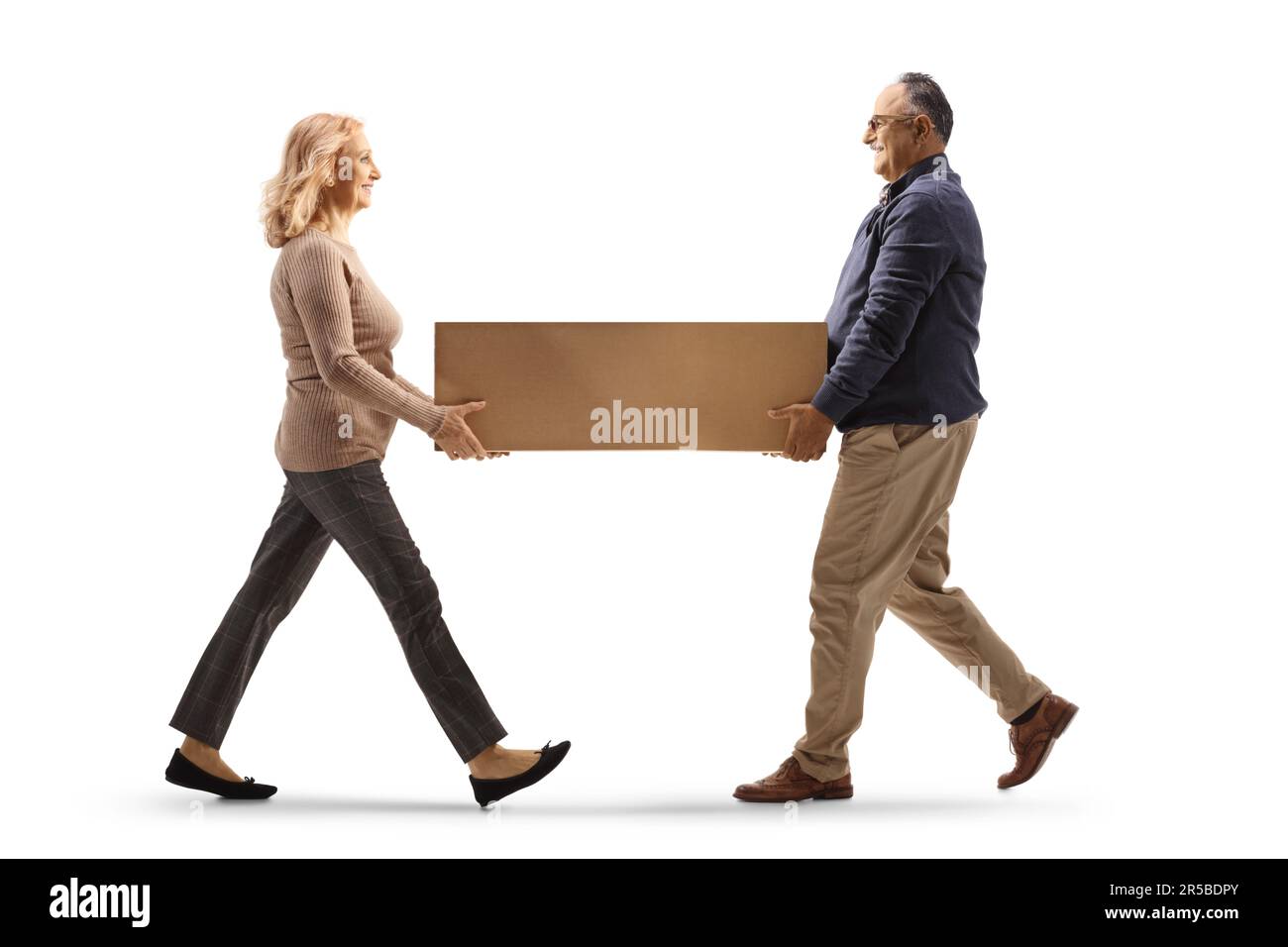 Prise de vue sur toute la longueur d'un homme et d'une femme matures portant une boîte en carton isolée sur fond blanc Banque D'Images