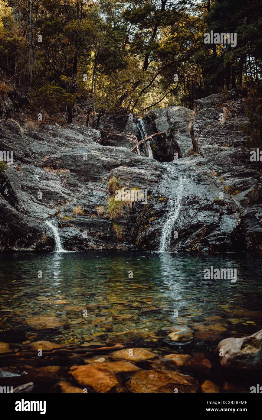 Une scène en plein air tranquille avec un plan d'eau entouré de grands rochers et arbres Banque D'Images