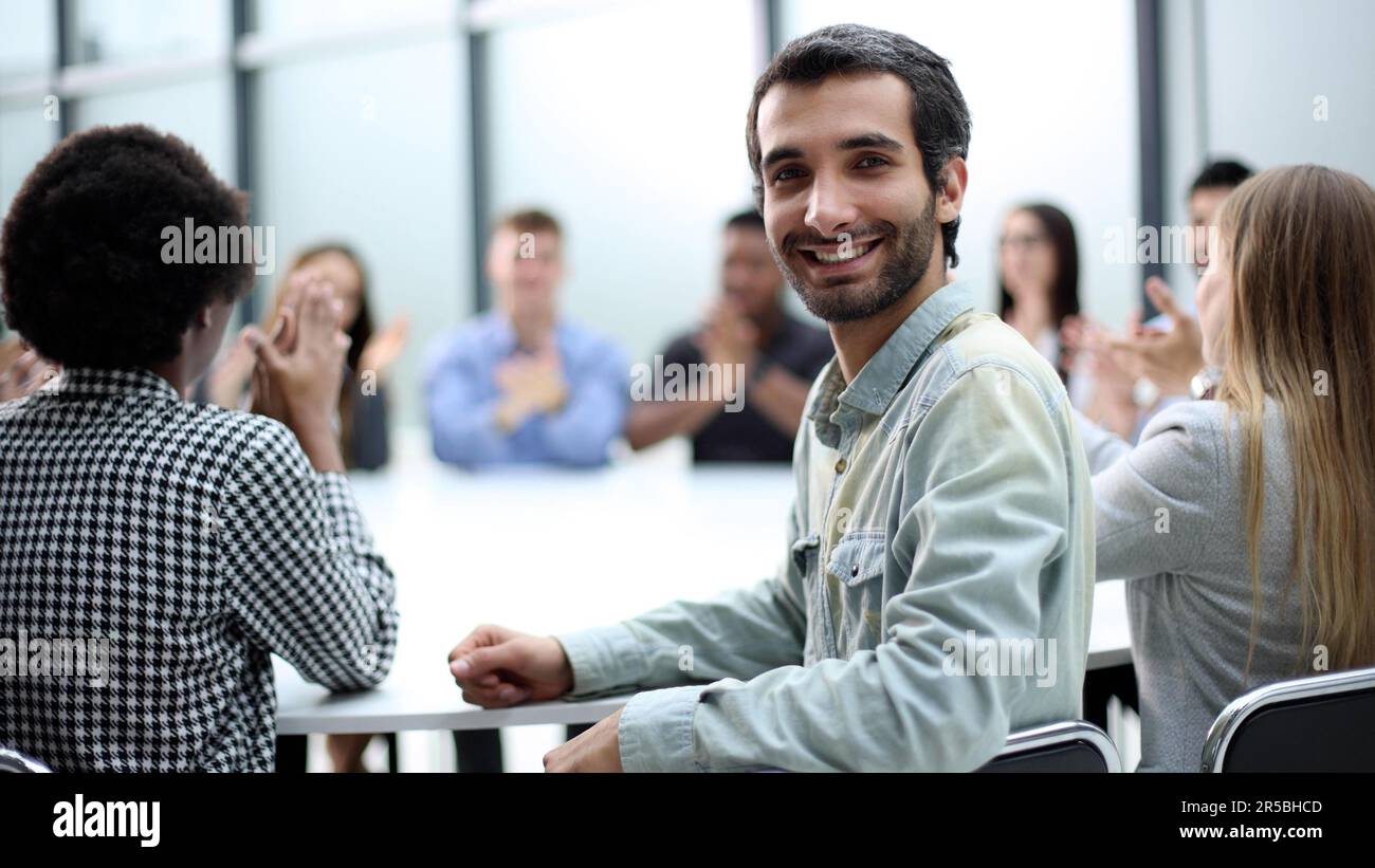 un homme regarde la caméra dans l'arrière-plan de ses collègues Banque D'Images