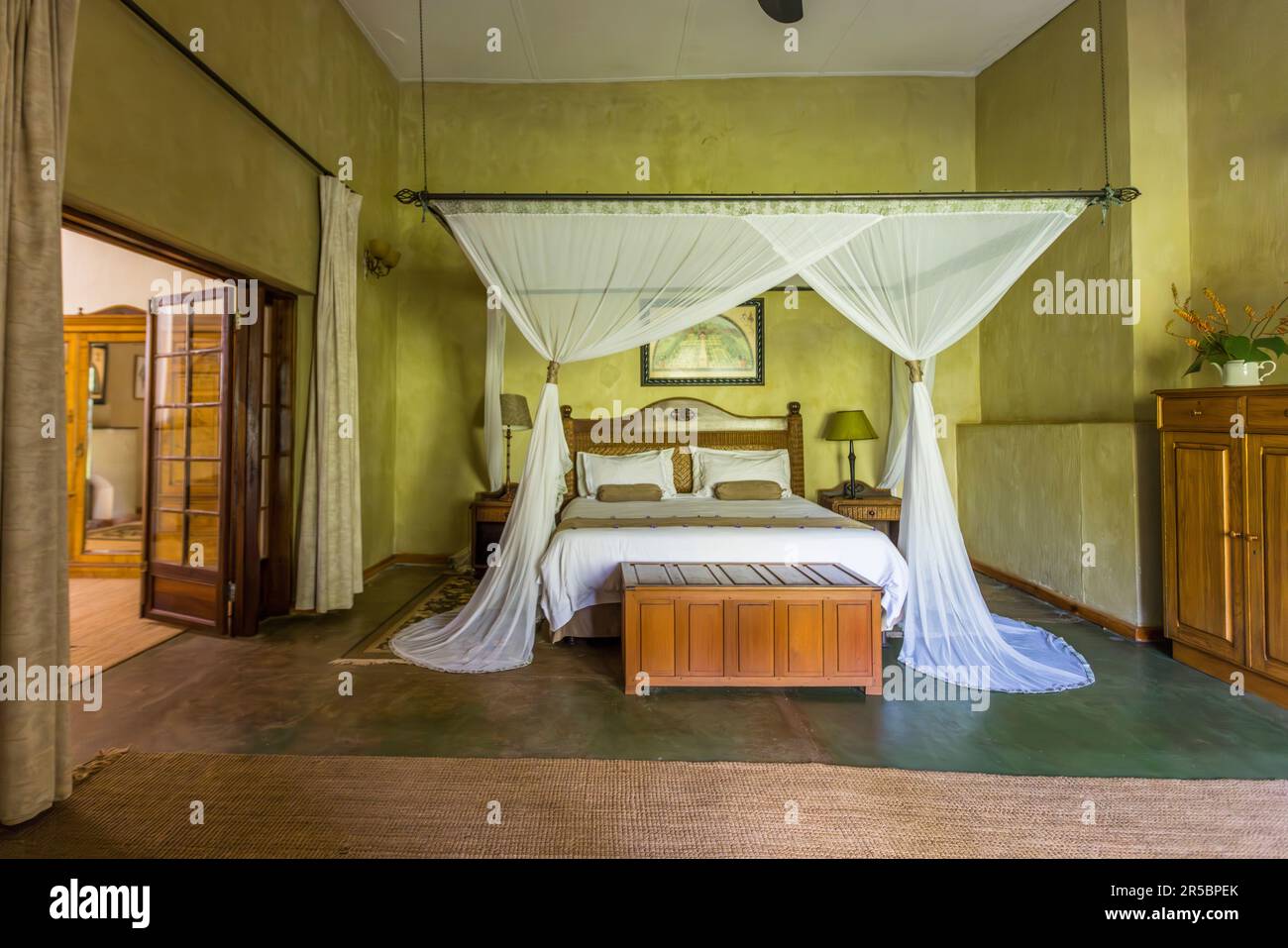 Une chambre d'hôtes spacieuse avec son propre accès au jardin, "The Planters Room", abritait autrefois la gouvernante au Huntingdon House sur le domaine de Satemwa près de Thyolo, au Malawi. Construit vers 1935, le manoir ne propose que cinq chambres d'hôtes, meublées dans un style colonial, et est l'ancien foyer de la famille qui possède encore aujourd'hui la plantation de thé et de café de Satemwa. Banque D'Images
