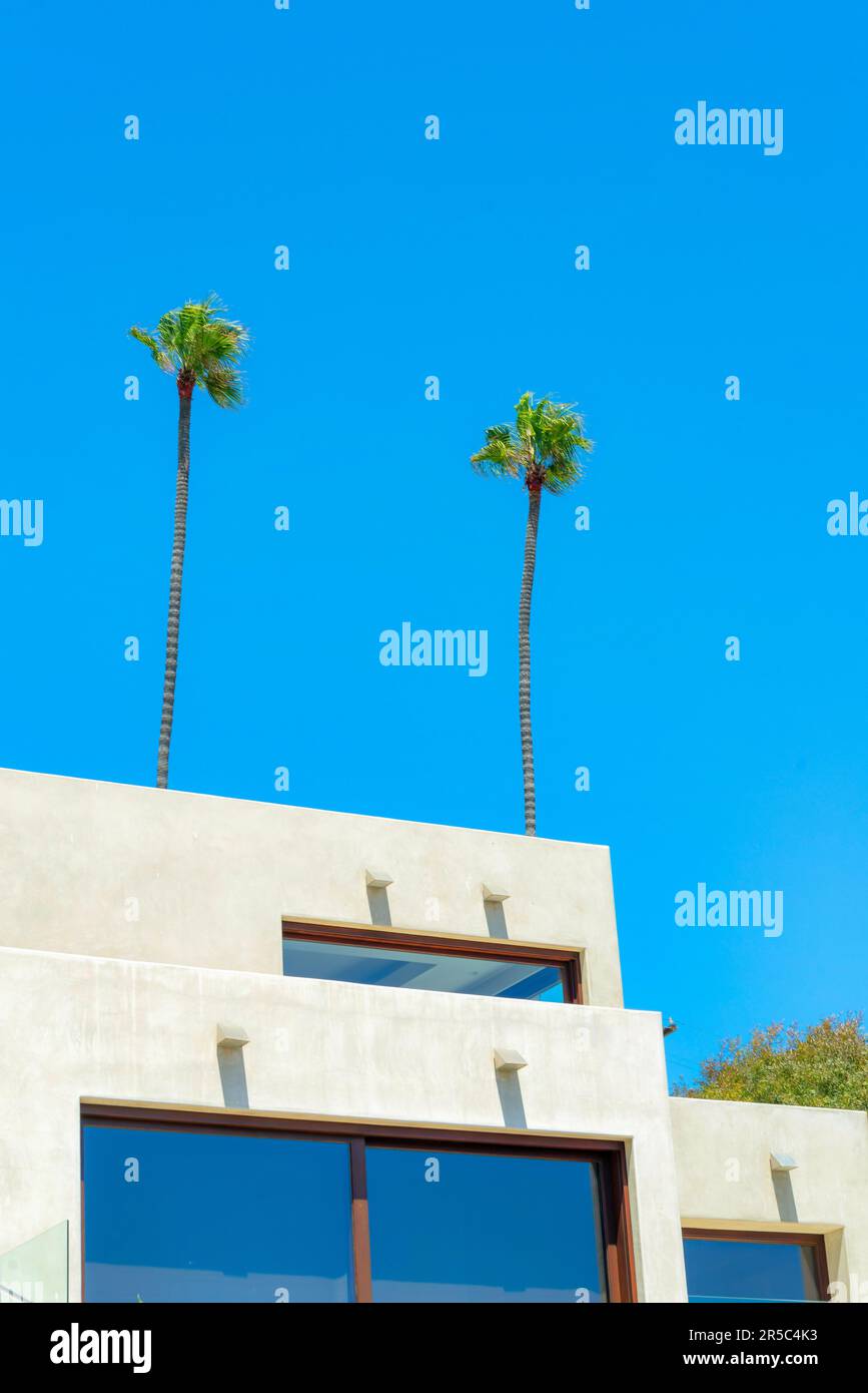 Une maison de plage blanche entourée de verdure sous un ciel bleu et la lumière du soleil Banque D'Images