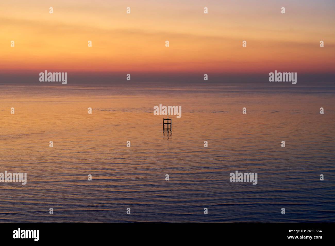 Une vue abstraite orientée horizontalement d'une structure en bois dans une mer calme au lever du soleil Banque D'Images