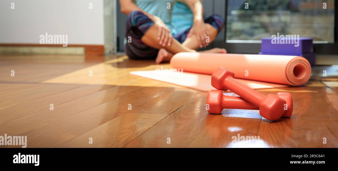 Haltères et tapis d'exercice de yoga sur le plancher en bois de la salle de gym, intérieur du studio Pilates, concept d'entraînement et de fitness Banque D'Images