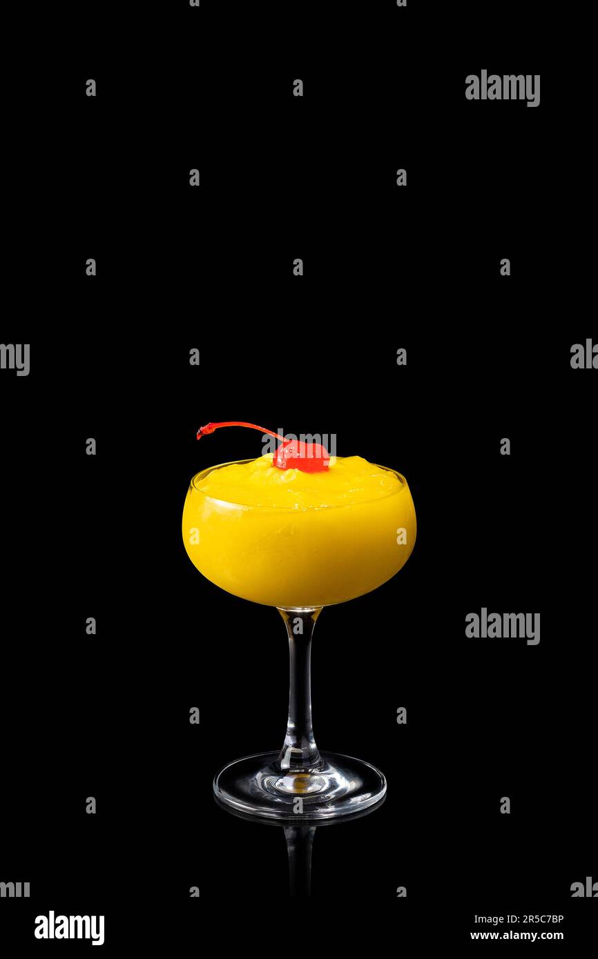 Verre de mangue ananas cocktail Daiquiri avec cerise rouge isolée sur fond noir. Cocktail alcoolisé frais. Banque D'Images