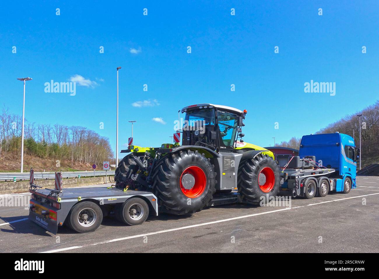 AACHEN, NRW, ALLEMAGNE - 29 mars 2019: Transport lourd d'un gros tracteur sur un camion de remorque spécial à bas chargeur, vue sur la route de stationnement sur une autoroute. Banque D'Images