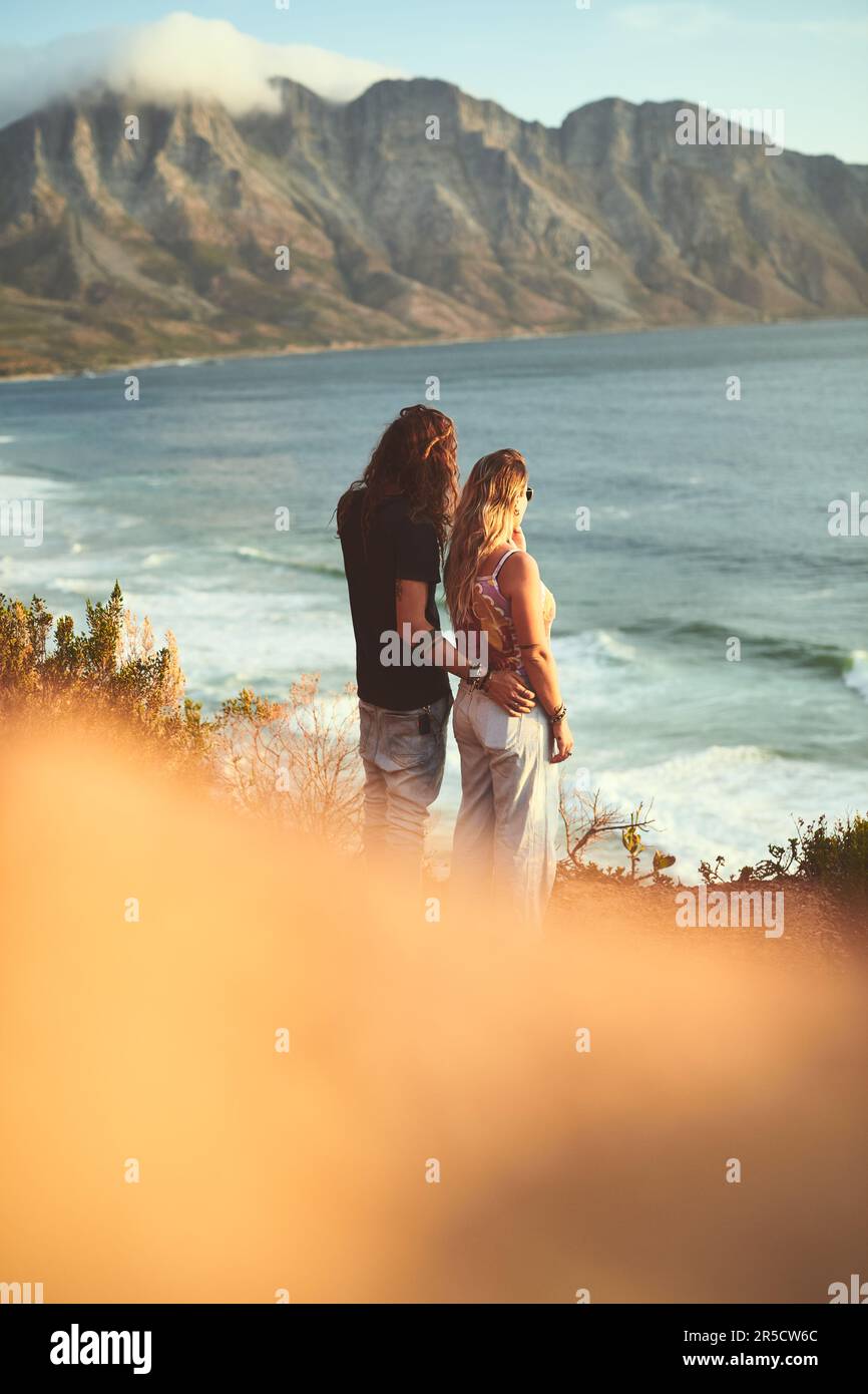 Le lien avec mon amour. un jeune couple affectueux se tenant ensemble et regardant la mer pendant une journée à l'extérieur. Banque D'Images