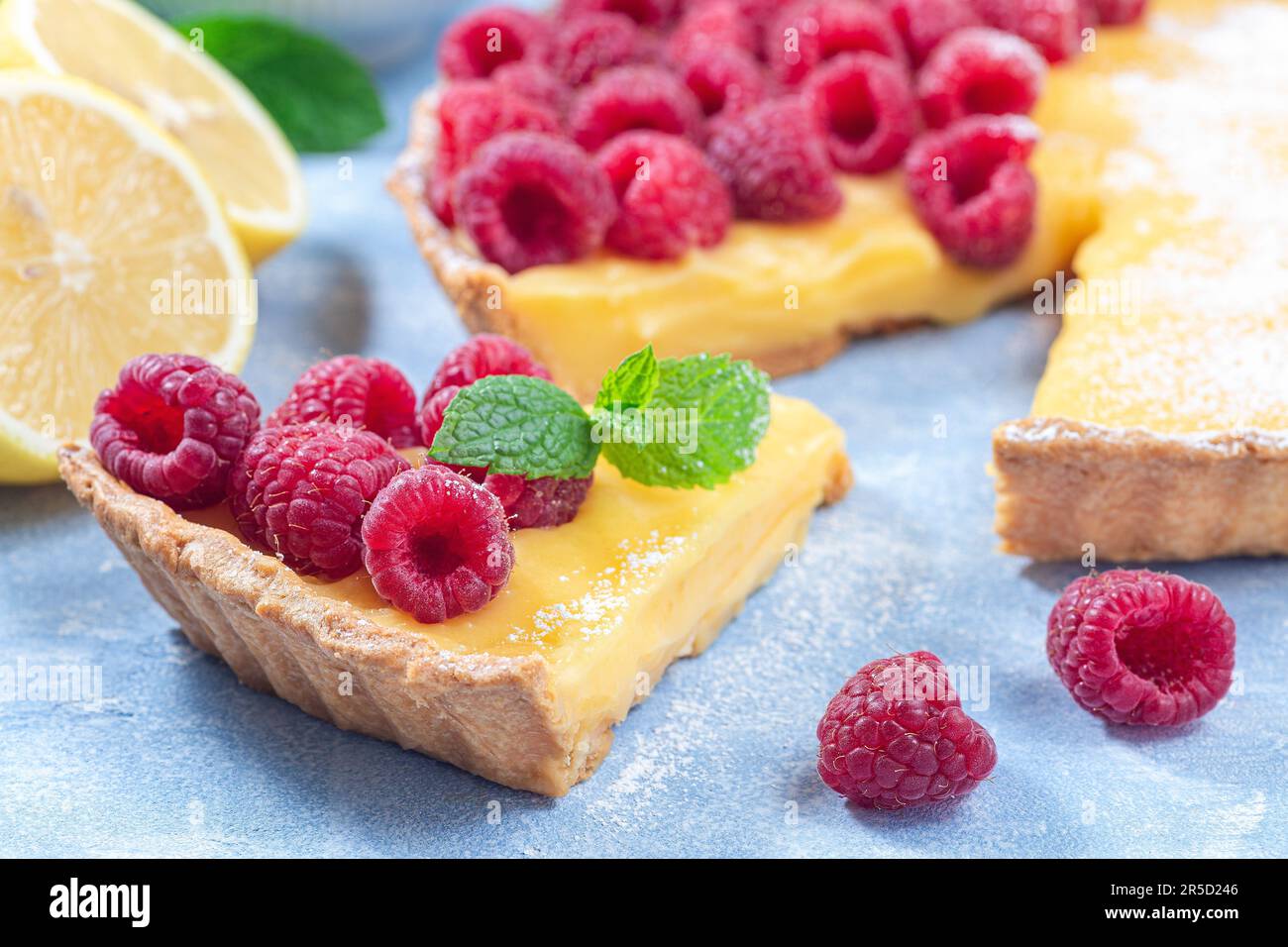 Tarte au citron, garnie de framboise fraîche, sucre glace et menthe, horizontale, gros plan Banque D'Images