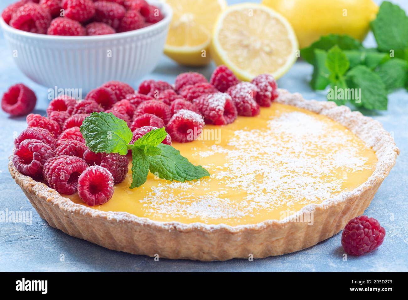 Tarte au citron, garnie de framboise fraîche, sucre glace et menthe, horizontale Banque D'Images