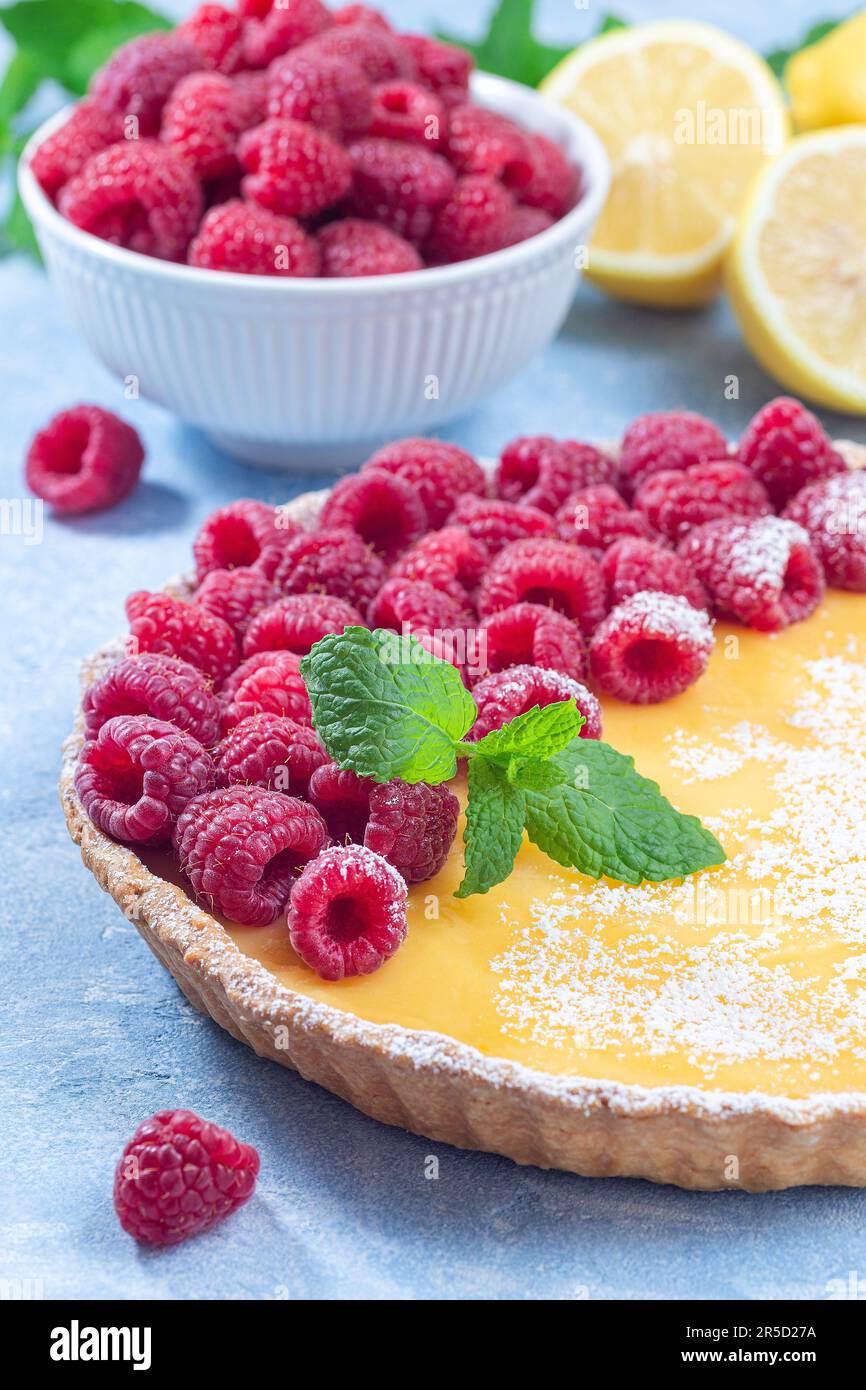 Tarte au citron, garnie de framboise fraîche, sucre glace et menthe, verticale Banque D'Images