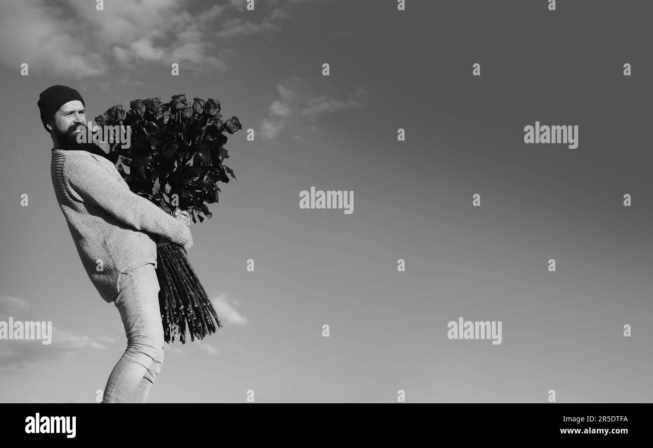 Homme avec bouquet de fleurs de roses. L'homme heureux tient un grand bouquet de roses rouges, proposer à l'ami le jour. Un gars romantique célèbre la Saint Valentin Banque D'Images