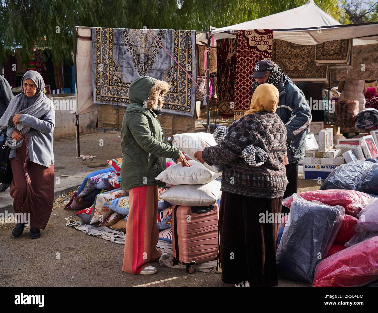 Sousse, Tunisie, 22 janvier 2023: Les clients examinent les marchandises dans une cabine vendant des coussins, des draps et des tapis sur le marché local de Sousse Banque D'Images