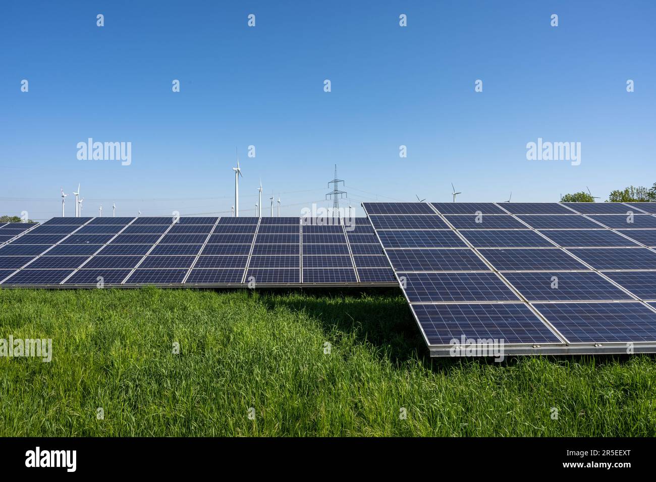 Centrale solaire avec lignes électriques et éoliennes dans le dos vu en Allemagne Banque D'Images