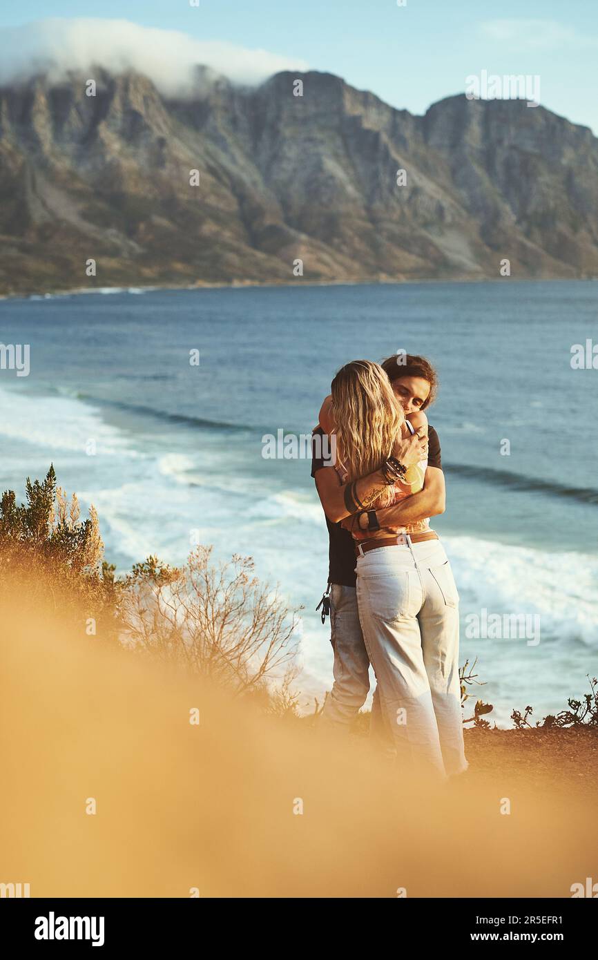 Vous, moi et la mer. un jeune couple affectueux se tenant ensemble et s'embrassant sur le flanc de la montagne près de la mer. Banque D'Images