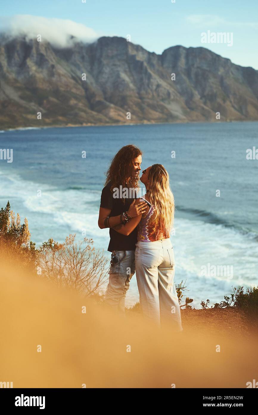 Vous avez tout ce dont j'ai besoin. un jeune couple affectueux se tenant sur le flanc d'une montagne près d'une mer ensemble pendant une journée à l'extérieur. Banque D'Images