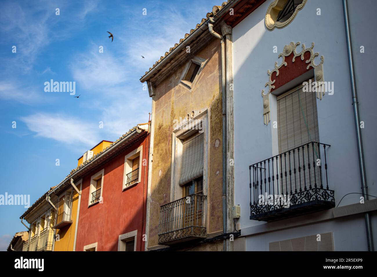 Façades de maisons colorées typiques dans le centre historique de Caravaca de la Cruz, à Murcie, en Espagne, avec des hirondelles volant dans le ciel bleu Banque D'Images