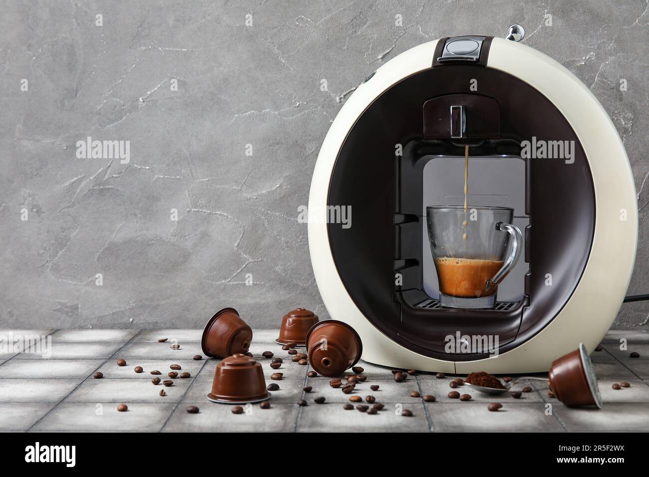 Cafetière capsule moderne avec expresso, tasse, dosettes et haricots sur  table blanche Photo Stock - Alamy