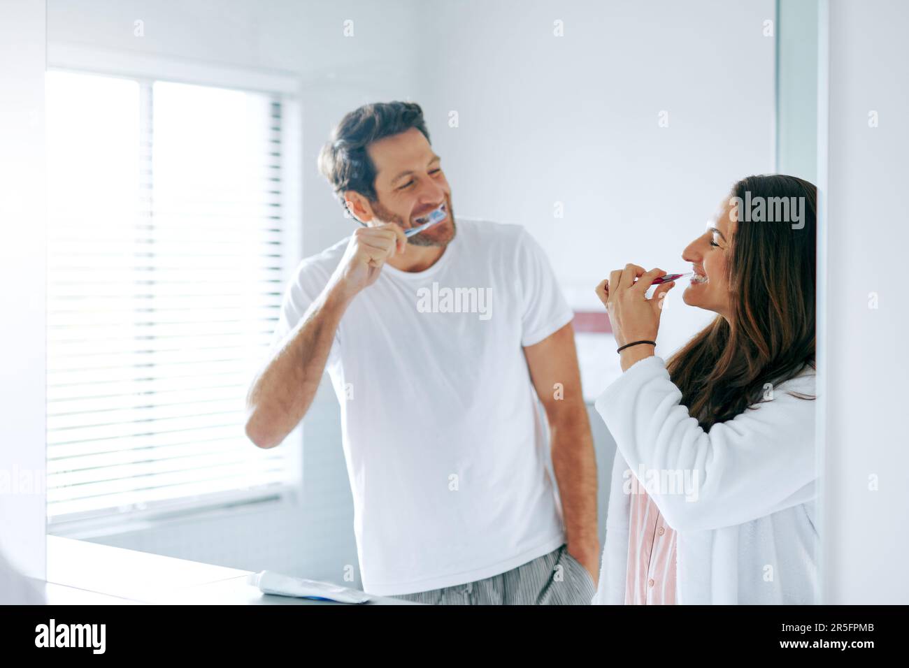 Le premier qui rit est le perdant. un couple se brossant les dents dans la salle de bains à la maison ensemble. Banque D'Images