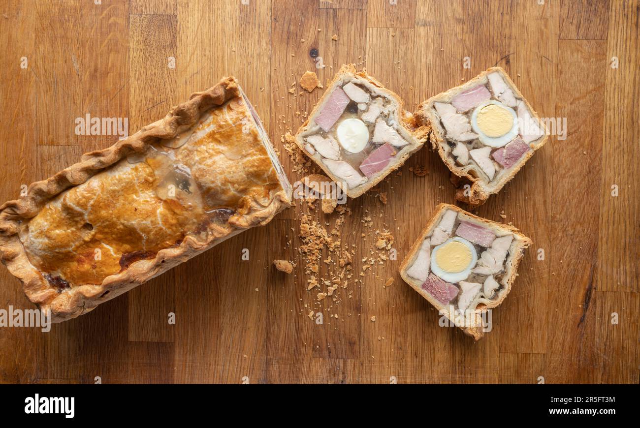 Jambon de poulet salé et tarte aux œufs présentés avec trois tranches appétissantes sur une planche à découper en bois. Banque D'Images