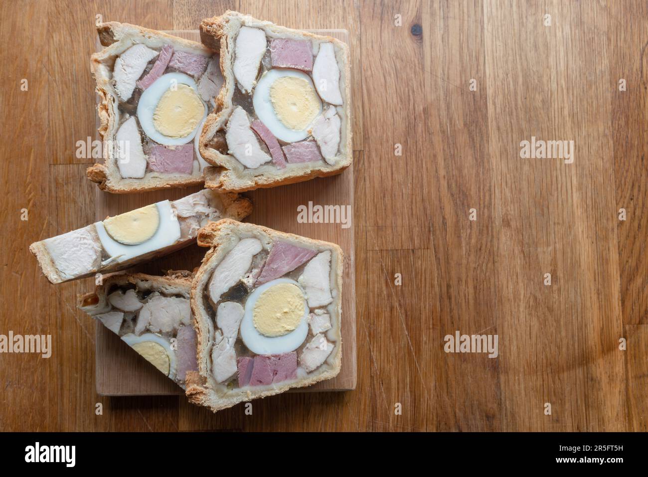 Appétissant jambon de poulet et tarte aux œufs présentés avec de belles tranches sur un petit panneau en bois, prêt à être apprécié. Banque D'Images