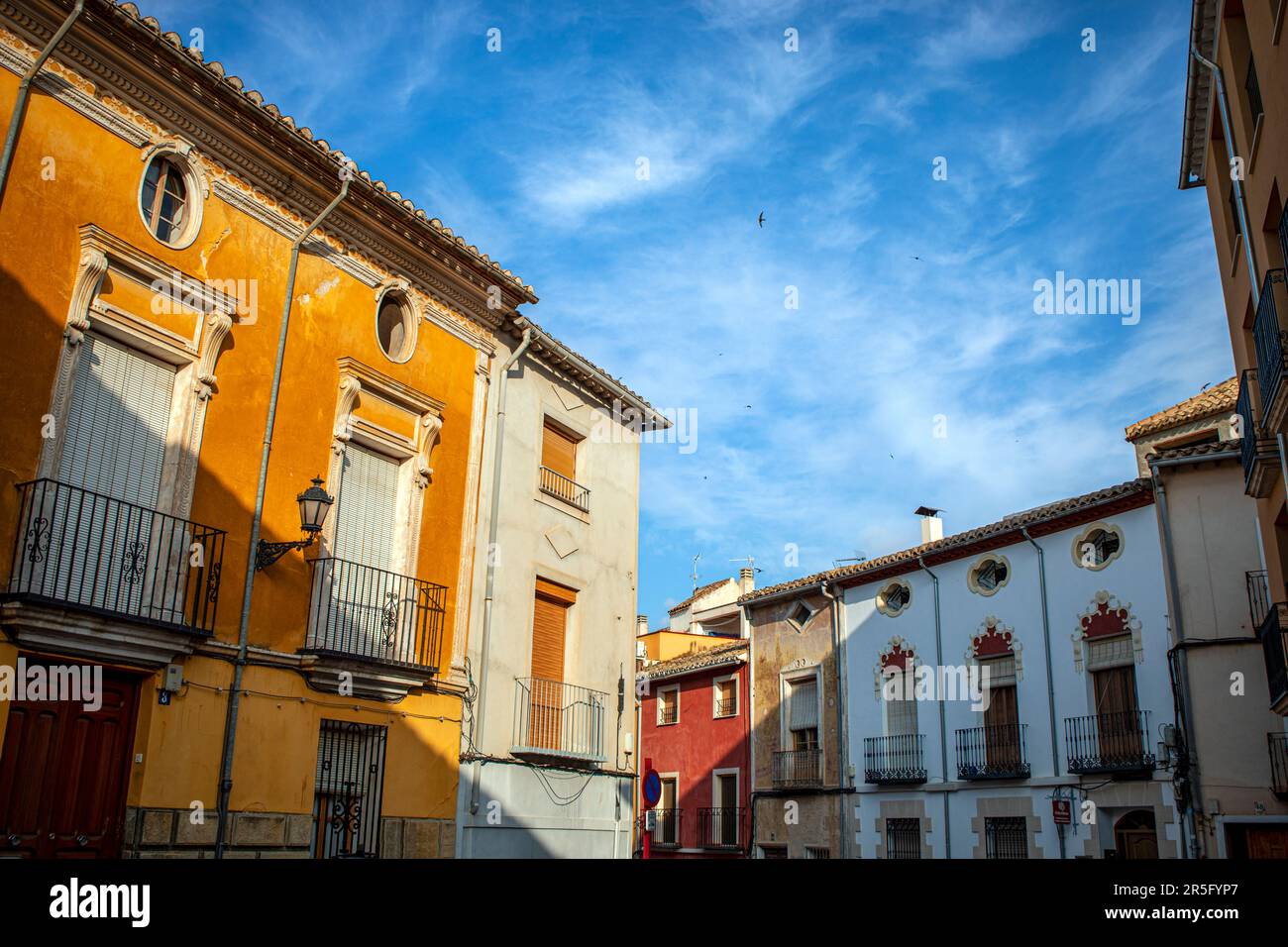 Façades de maisons colorées typiques dans le centre historique de Caravaca de la Cruz, à Murcie, en Espagne, avec des hirondelles volant dans le ciel bleu Banque D'Images