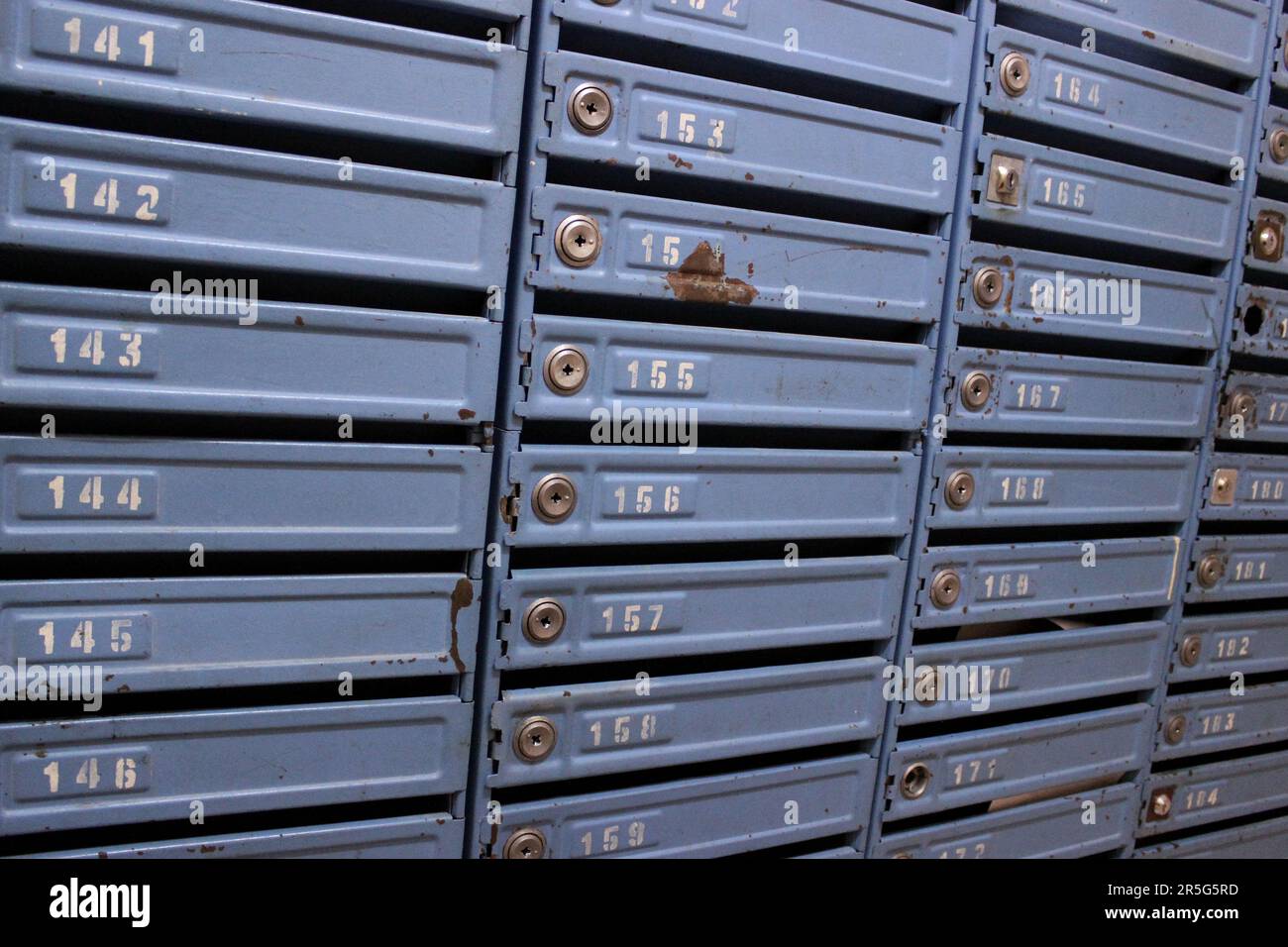 Rares cellules de courrier d'abonné numérotées dans un immeuble résidentiel avec des portes rouillées Banque D'Images