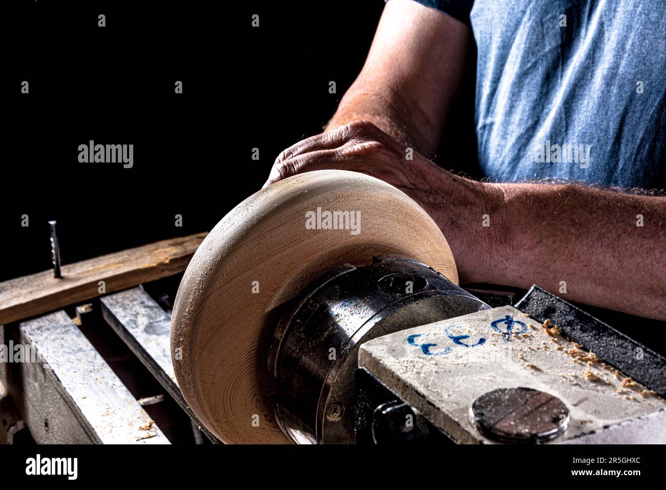 Artisan créant un bol en bois sur le tour. Image dans l'atelier. Arrière-plan noir. Banque D'Images