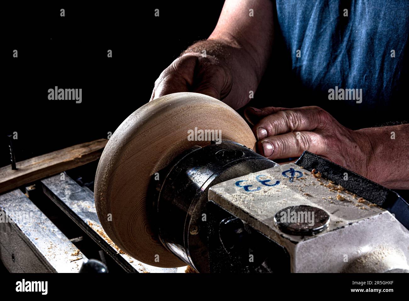 Artisan créant un bol en bois sur le tour. Image dans l'atelier.arrière-plan noir. Banque D'Images