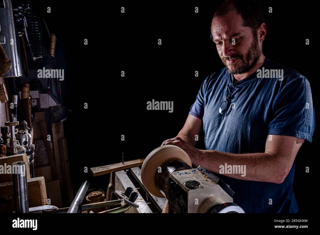 Artisan créant un bol en bois sur le tour. Image dans l'atelier. Créer un bol en bois sur le tour.arrière-plan noir. Banque D'Images