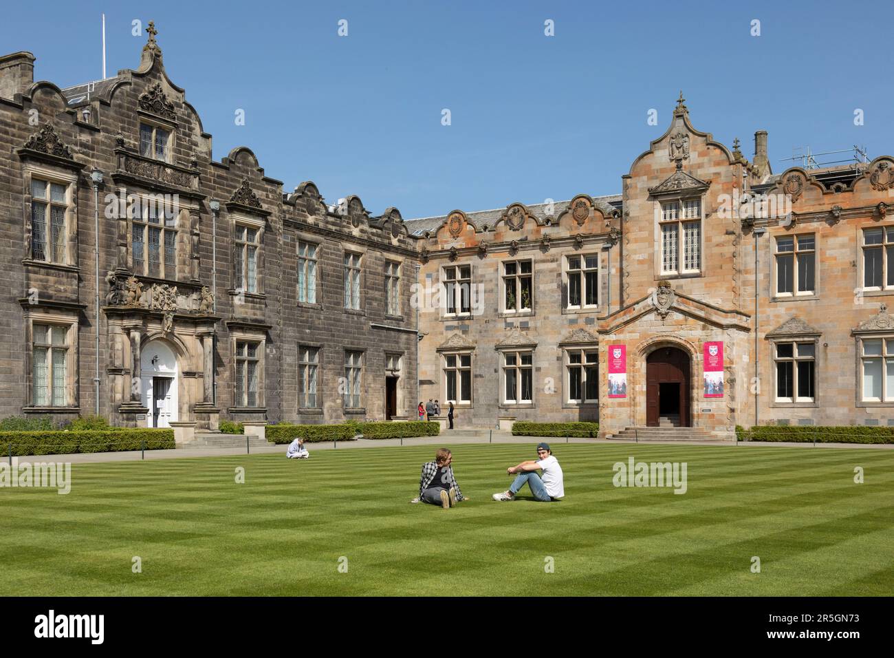 Les jeunes sont assis sur la pelouse bien entretenue du Quadrangle de St Salvator, qui fait partie de l'université historique de St Andrews à Fife, en Écosse. Banque D'Images