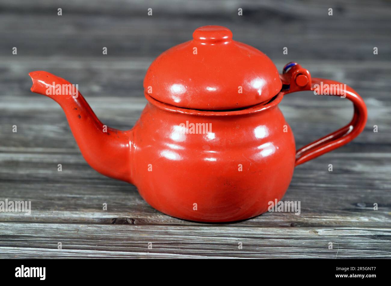Théière rétro vintage de style ancien, théière rouge isolée sur fond en bois, contenant pour préparer et servir du thé avec une poignée et une ouverture en forme de forme Banque D'Images