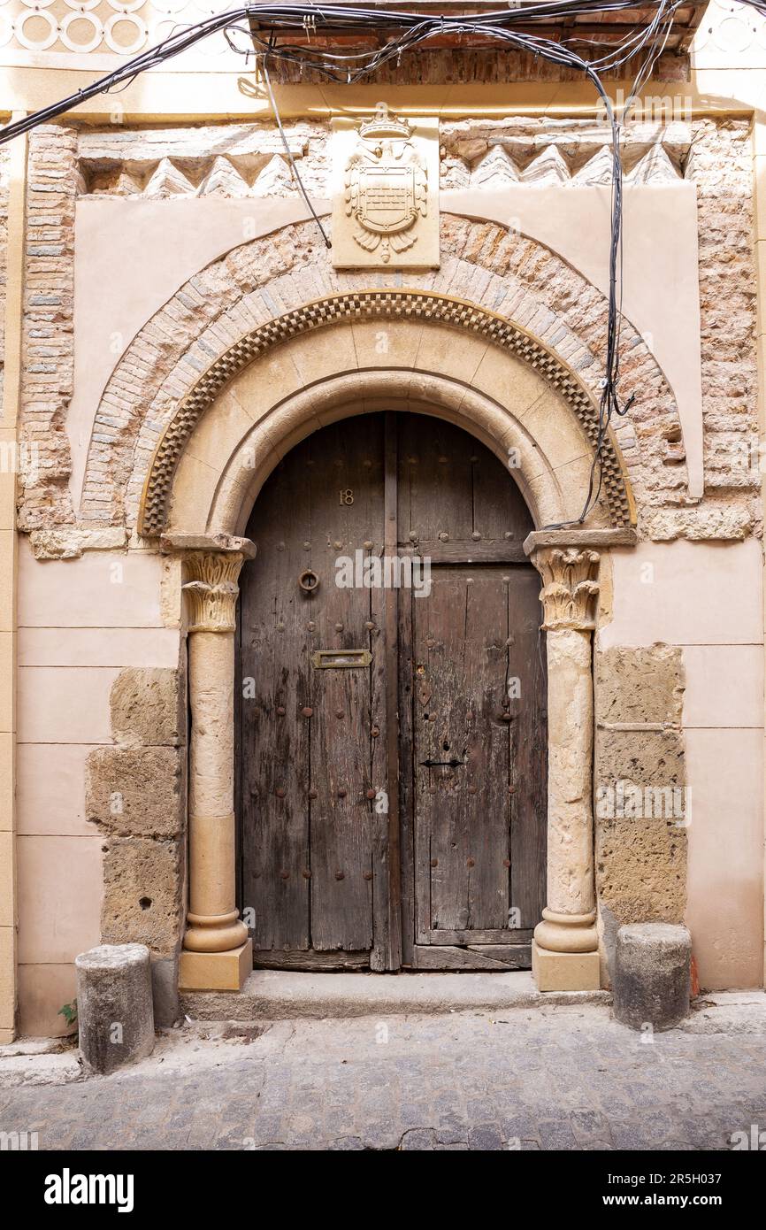Vieilles portes médiévales en bois avec arches sculptées en pierre et armoiries au-dessus à Ségovie, Espagne. Banque D'Images