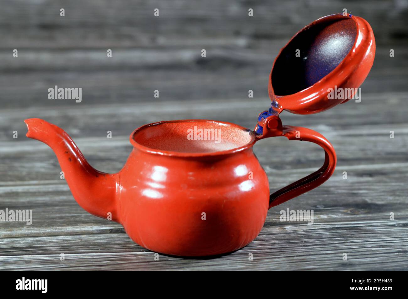 Théière rétro vintage de style ancien, théière rouge isolée sur fond en bois, contenant pour préparer et servir du thé avec une poignée et une ouverture en forme de forme Banque D'Images