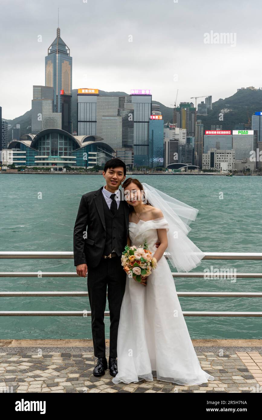 Un couple qui vient de se marier pose pour Une photo sur fond de l'île de Hong Kong, Hong Kong, Chine. Banque D'Images