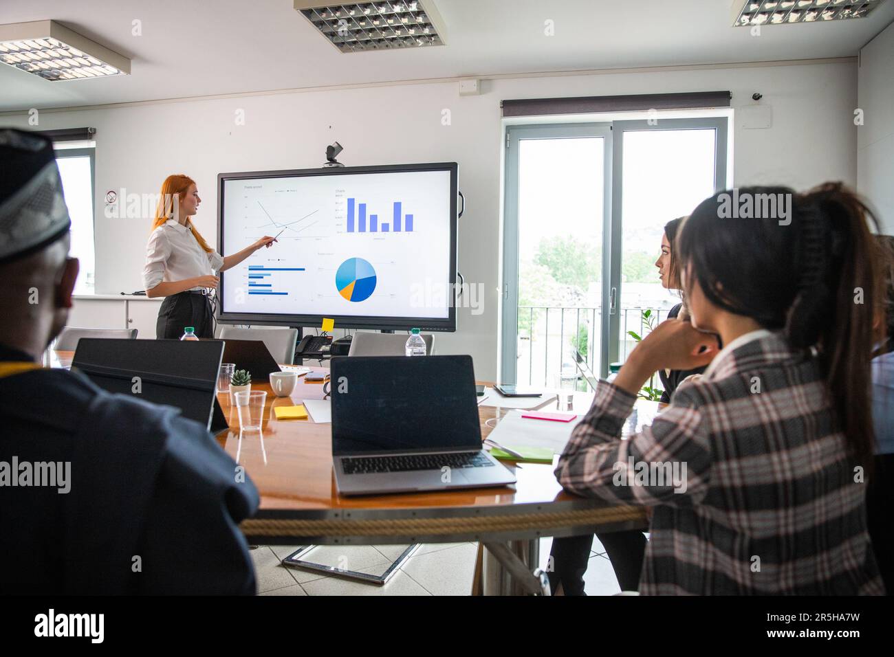 Une femme d'affaires explique des graphiques à ses collègues lors d'une réunion internationale Banque D'Images