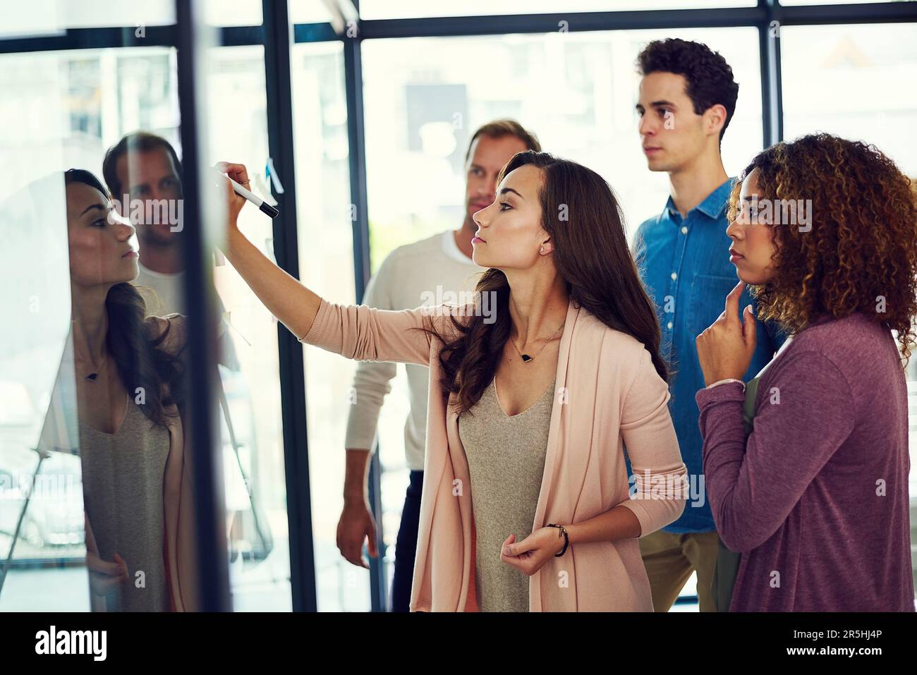Travailler sur un autre plan ambitieux et audacieux. un groupe de jeunes designers remue-méninges avec des notes sur un mur de verre dans un bureau. Banque D'Images