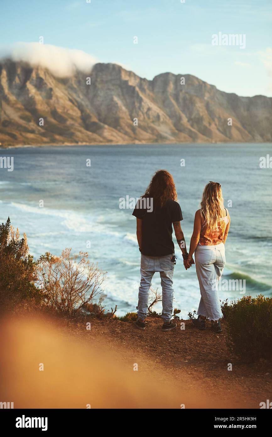 Cette vue n'est pas vraiment super. Prise de vue en longueur d'un jeune couple affectueux debout ensemble et regardant la mer pendant une journée à l'extérieur. Banque D'Images