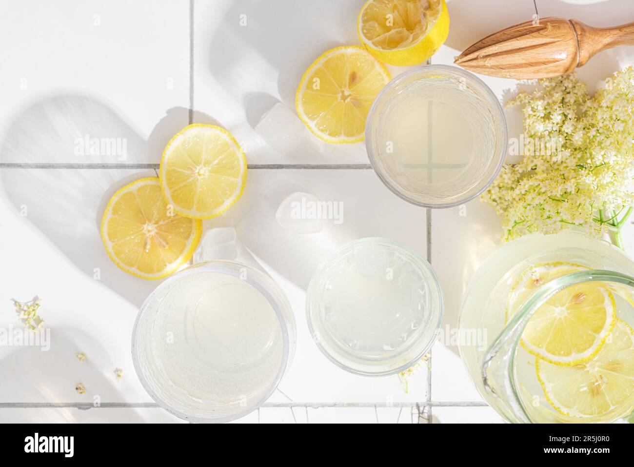 Micktail de rafraîchissements d'été avec citrons, fleurs de sureau et glaçons en verres sur fond blanc et lumière intense Banque D'Images