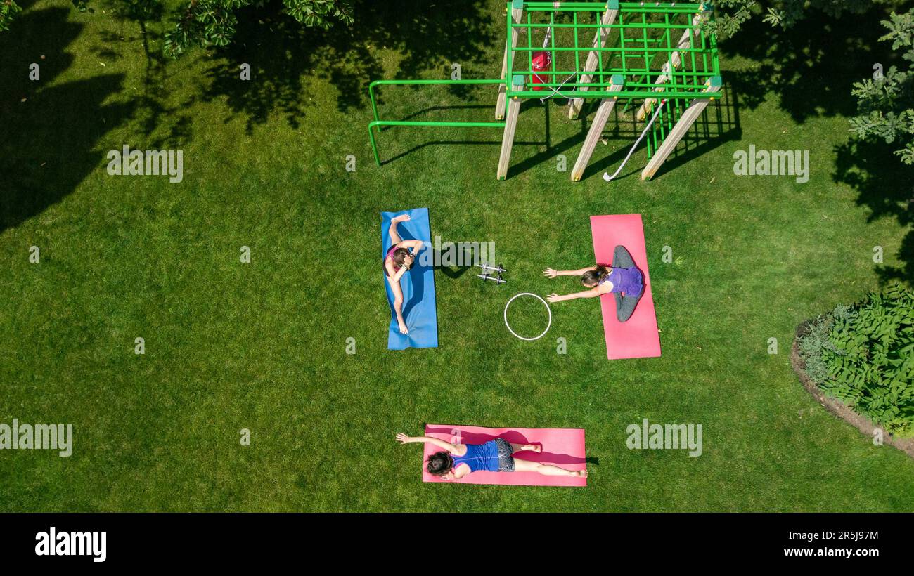 Groupe de filles actives faisant de l'entraînement de forme physique à l'extérieur dans le parc, les femmes en bonne santé s'exerçant sur l'herbe verte, vue aérienne de drone d'en haut Banque D'Images