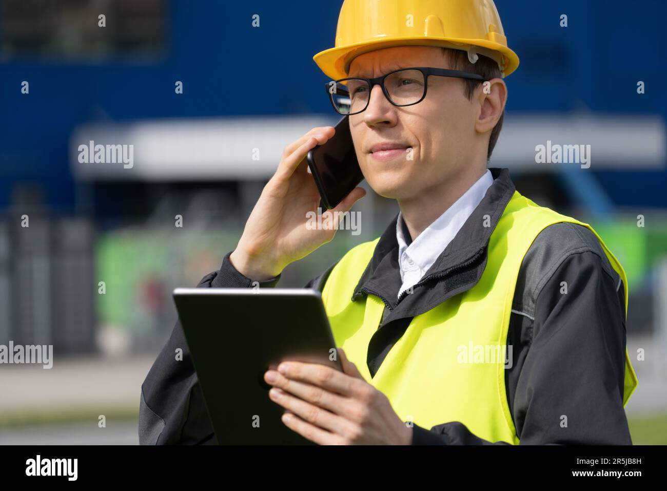 Employé avec téléphone et tablette numérique sur un fond de centre logistique Banque D'Images