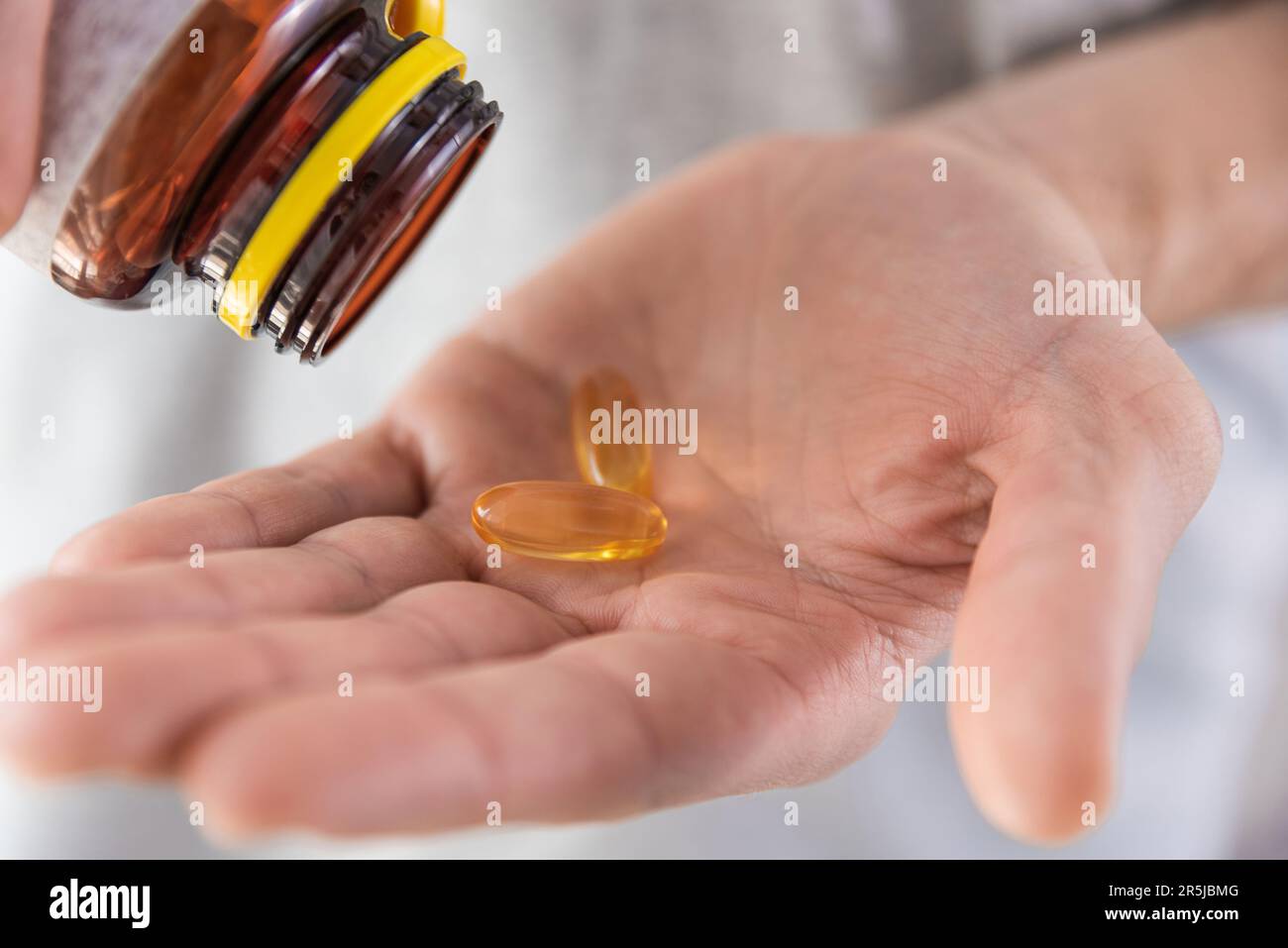 Homme versant des capsules d'huile de poisson avec des oméga-3, vitamine D dans la main à partir d'une bouteille de médicament. Supplément nutritionnel. Concept de soutien et de traitement de la santé. Banque D'Images