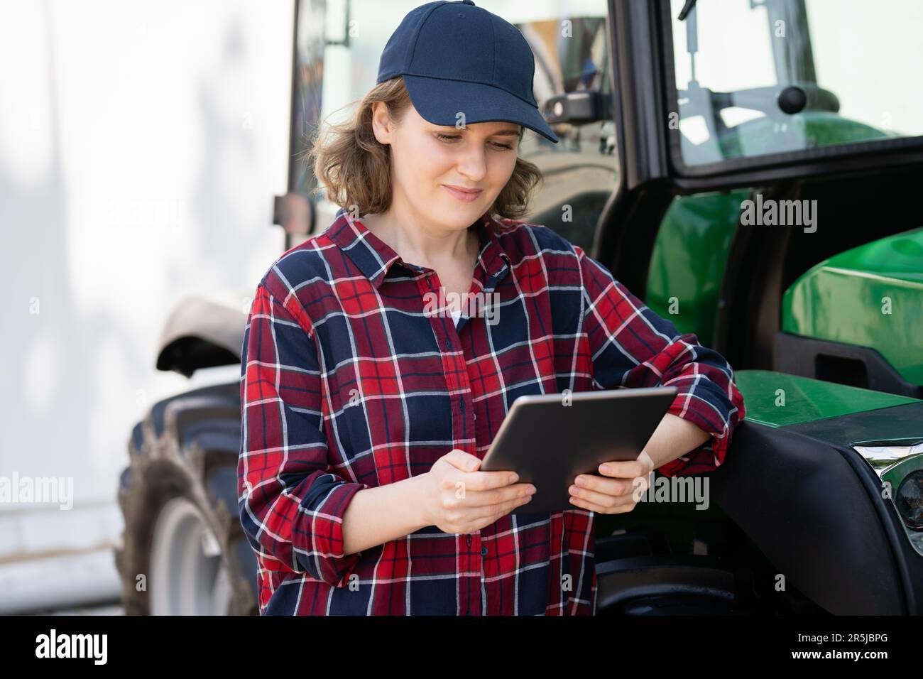 Femme agriculteur avec une tablette numérique sur le fond d'un tracteur agricole Banque D'Images
