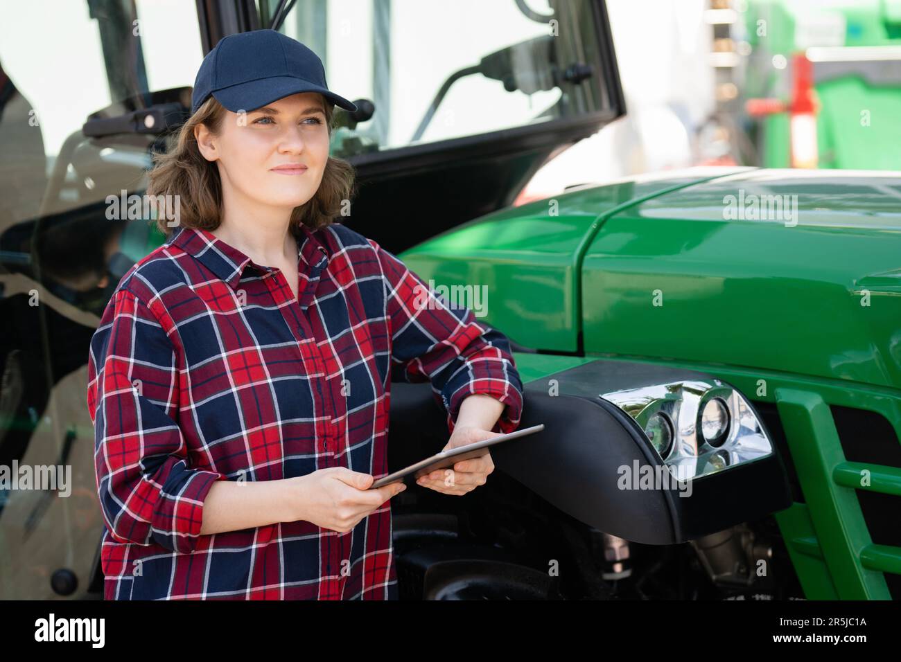 Femme agriculteur avec une tablette numérique sur le fond d'un tracteur agricole Banque D'Images