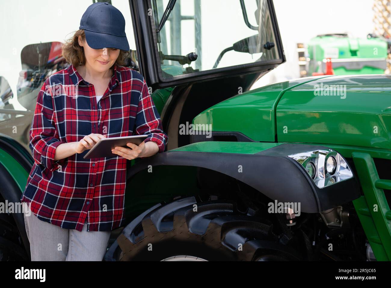 Femme agriculteur avec une tablette numérique sur le fond d'un tracteur agricole Banque D'Images