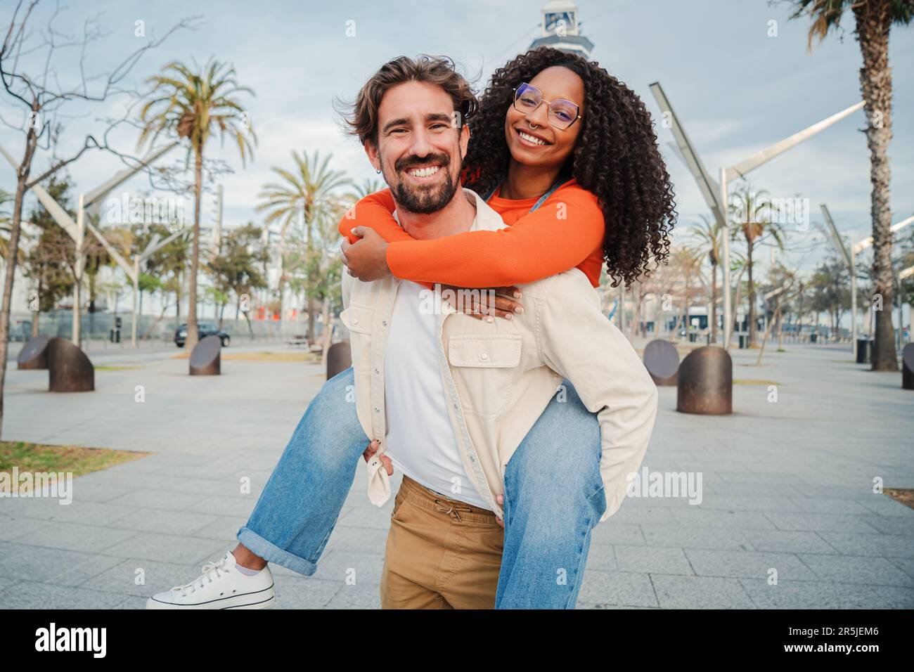 Couple multiracial s'embrassant et s'amusant. Homme caucasien donnant à sa petite amie afro-américaine une promenade romantique en pigeback en appréciant une belle journée ensemble. Homme souriant amoureux portant son dos à sa femme. Photo de haute qualité Banque D'Images