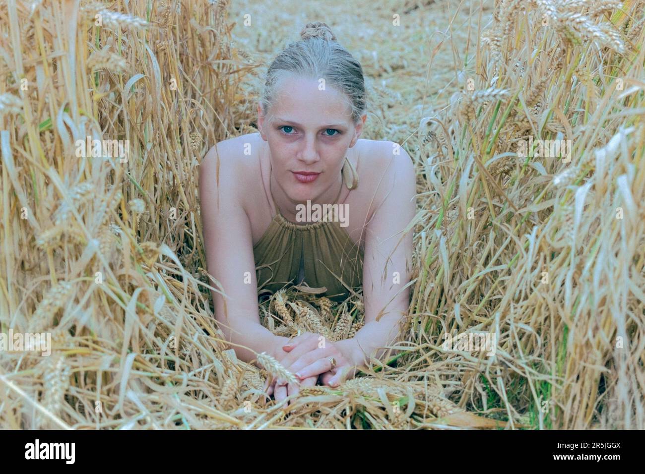 jeune femme mince et blonde aux cheveux au début de 20s posant pour le portrait dans le champ de blé 1990s Banque D'Images