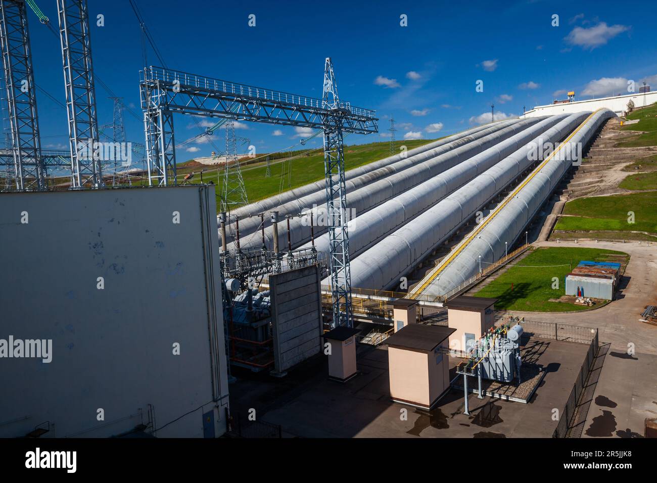 Les tuyaux et les tours électriques et les transformateurs de la centrale hydroélectrique contre le ciel bleu Banque D'Images